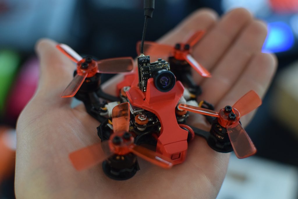 Drone, CES, Drone Rodeo. A bright orange drone sits in the palm of a pilot's hand.
